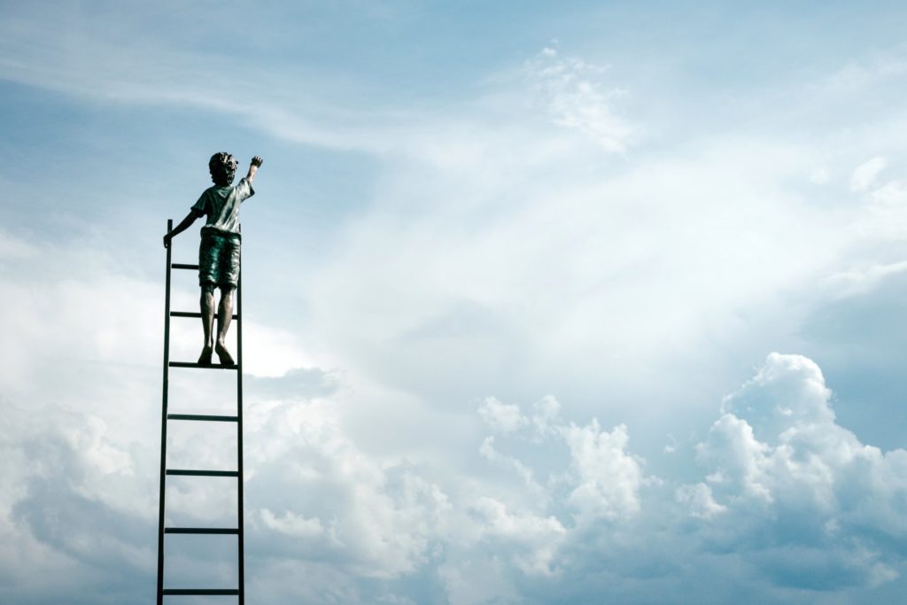 Blue cloudy sky with boy climbing ladder